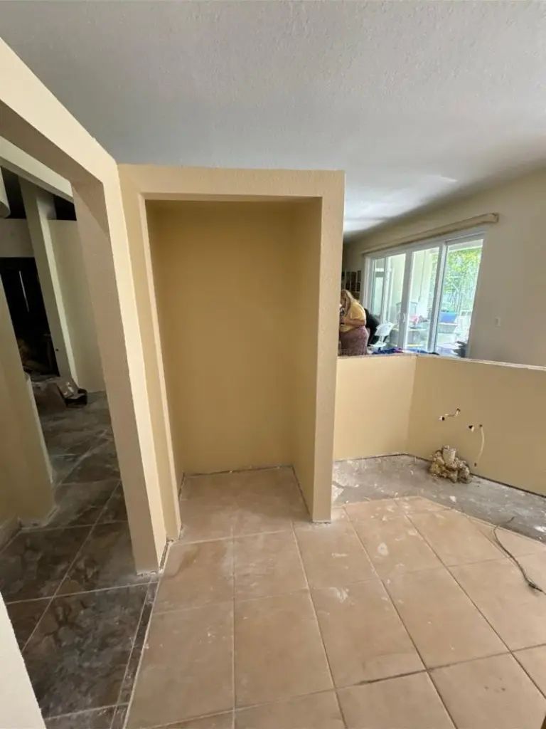 Interior space under renovation with a recessed drywall niche, tiled floors, and unfinished wall openings